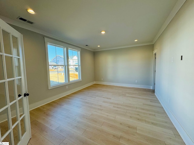 spare room featuring crown molding and light hardwood / wood-style floors