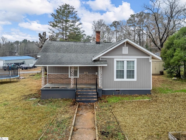 view of front facade featuring covered porch, a front yard, and a trampoline