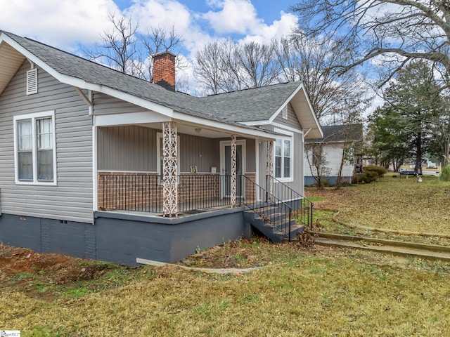 view of side of property featuring covered porch and a yard