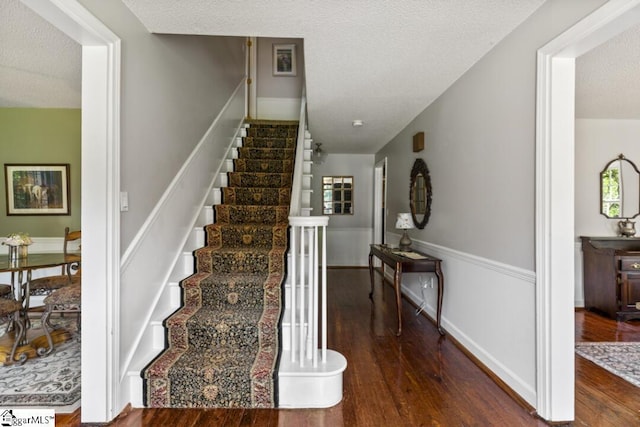 staircase featuring a textured ceiling and hardwood / wood-style flooring