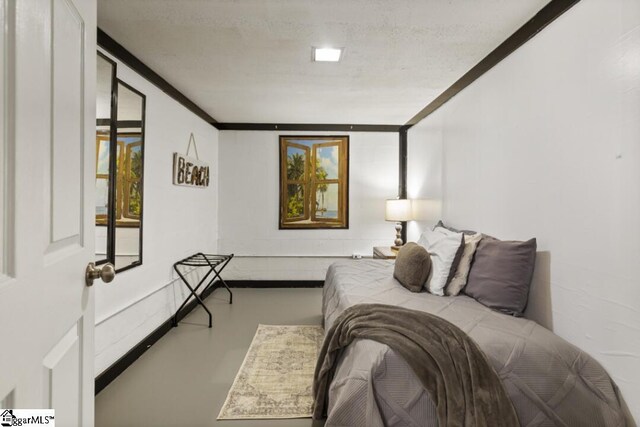 bedroom with concrete flooring, a textured ceiling, and ornamental molding