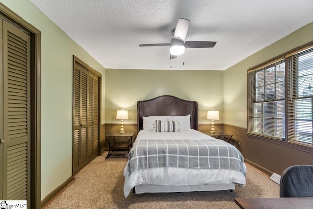 bedroom featuring a textured ceiling, ceiling fan, and light carpet