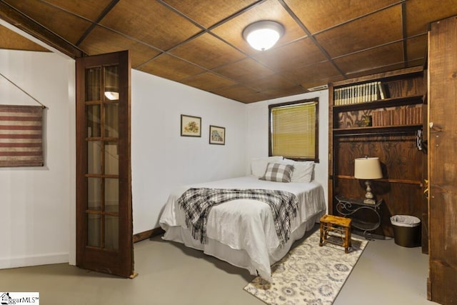 bedroom with concrete flooring and a paneled ceiling