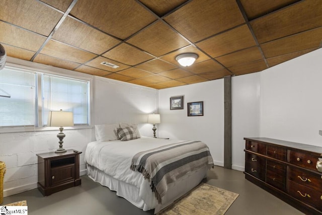 bedroom with concrete flooring and a paneled ceiling