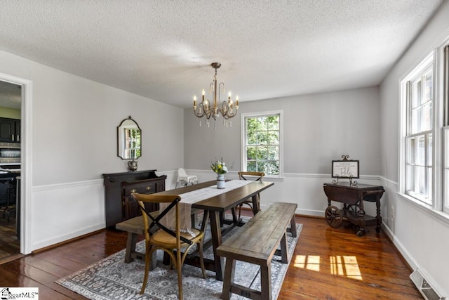 dining area with a notable chandelier, dark hardwood / wood-style floors, and a textured ceiling