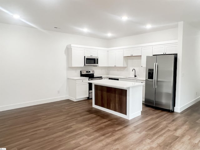 kitchen with dark hardwood / wood-style flooring, stainless steel appliances, sink, white cabinetry, and a kitchen island