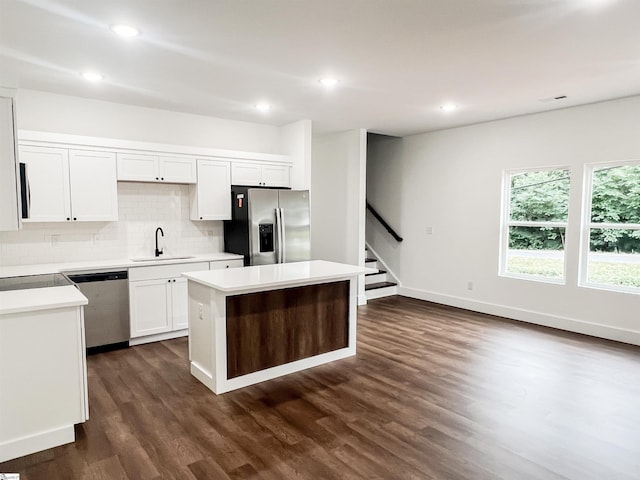 kitchen with sink, dark hardwood / wood-style floors, appliances with stainless steel finishes, a kitchen island, and white cabinetry