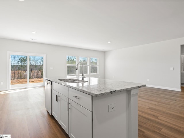 kitchen with dark wood-style floors, a healthy amount of sunlight, a sink, and light stone countertops