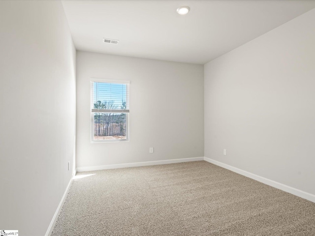 carpeted spare room with visible vents and baseboards