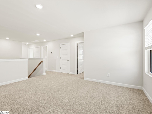 spare room featuring baseboards, recessed lighting, and light colored carpet