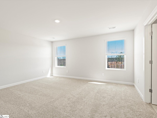 unfurnished room with light carpet, visible vents, and baseboards