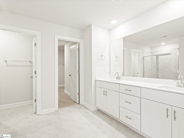 full bath featuring double vanity, a sink, a shower stall, and a spacious closet