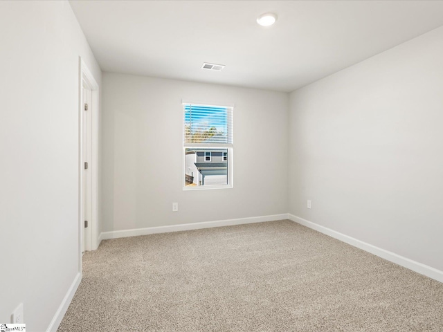 spare room with light colored carpet, visible vents, and baseboards