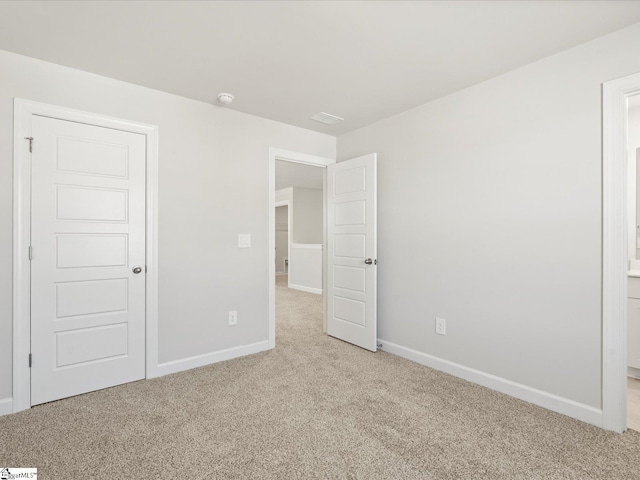 unfurnished bedroom with carpet floors, visible vents, baseboards, and ensuite bathroom