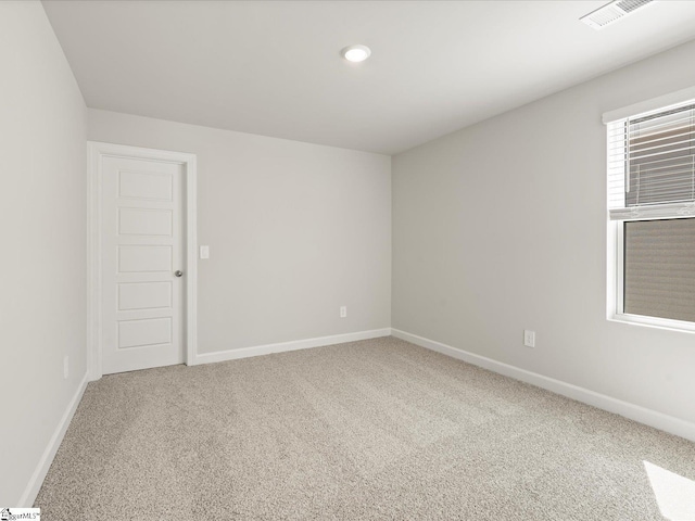 empty room with carpet floors, visible vents, and baseboards