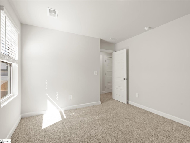 empty room featuring baseboards, visible vents, and carpet flooring