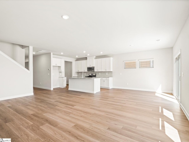 unfurnished living room featuring baseboards, recessed lighting, and light wood-style floors