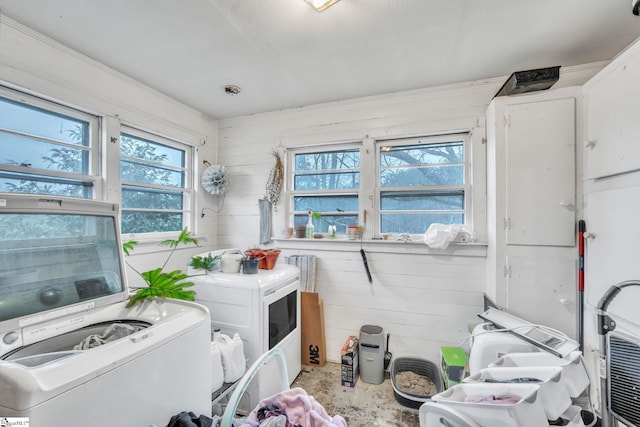 clothes washing area featuring independent washer and dryer and wood walls