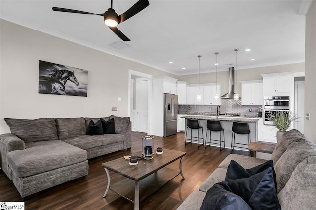 living room with ceiling fan, dark hardwood / wood-style flooring, sink, and ornamental molding