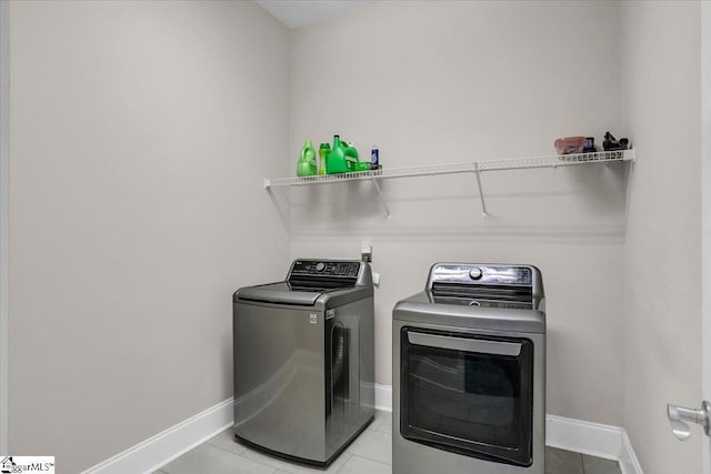 clothes washing area with washer and clothes dryer and light tile patterned floors