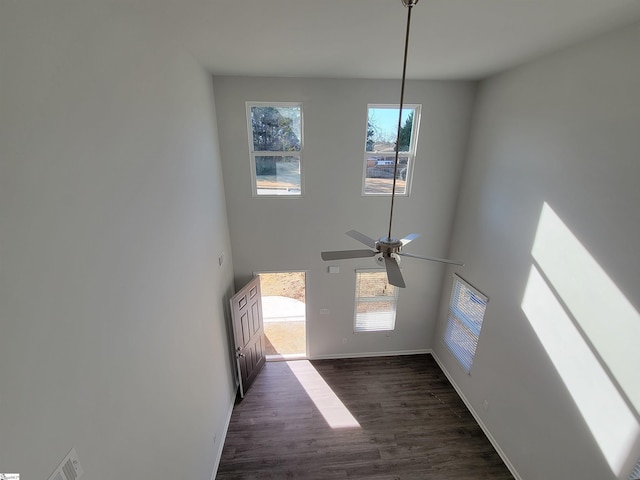 interior space featuring a towering ceiling, dark hardwood / wood-style flooring, and ceiling fan