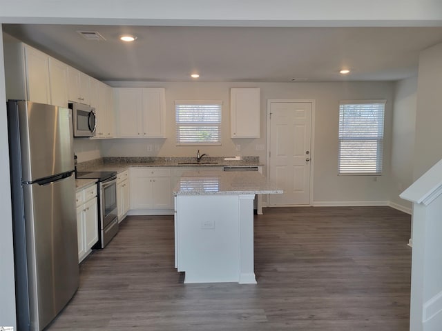 kitchen with light stone countertops, appliances with stainless steel finishes, a center island, and white cabinetry