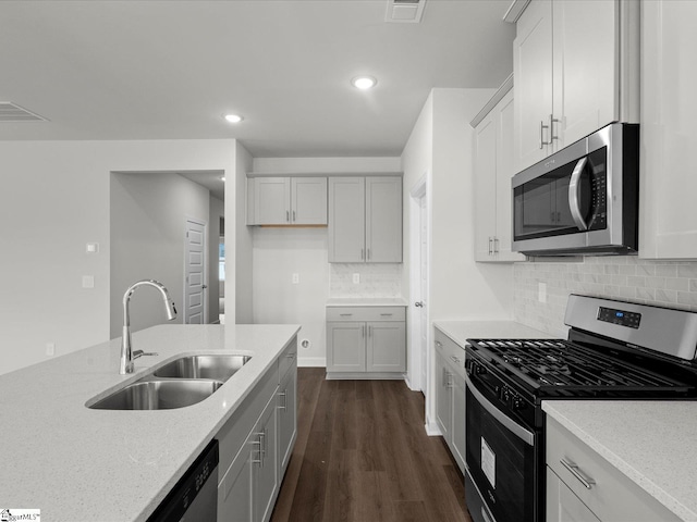 kitchen with appliances with stainless steel finishes, tasteful backsplash, sink, dark hardwood / wood-style flooring, and light stone counters