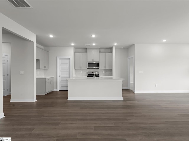 kitchen with tasteful backsplash, stainless steel appliances, dark hardwood / wood-style flooring, and a kitchen island with sink