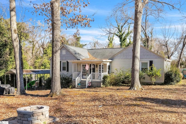 single story home with covered porch, a fire pit, and a carport