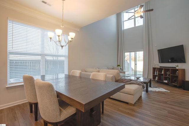 dining area featuring crown molding, wood-type flooring, and ceiling fan with notable chandelier