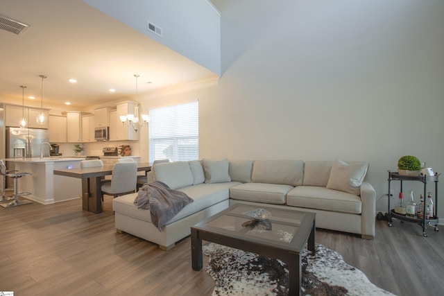 living room featuring a chandelier, wood-type flooring, and crown molding