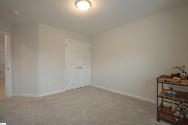 unfurnished bedroom with light carpet and a closet