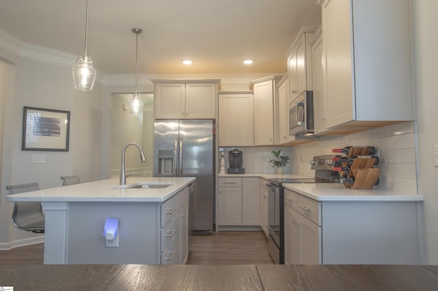 kitchen with a center island with sink, sink, decorative backsplash, appliances with stainless steel finishes, and decorative light fixtures