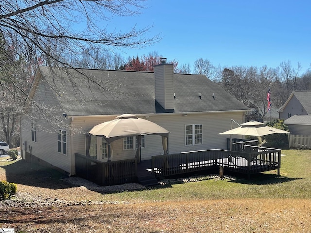 back of property with a wooden deck, a lawn, and a chimney