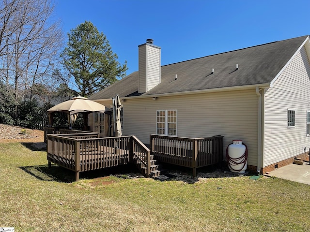 back of house featuring a deck, crawl space, a lawn, and a chimney