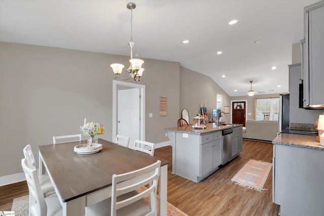 dining room with light wood-type flooring, ceiling fan with notable chandelier, lofted ceiling, and sink