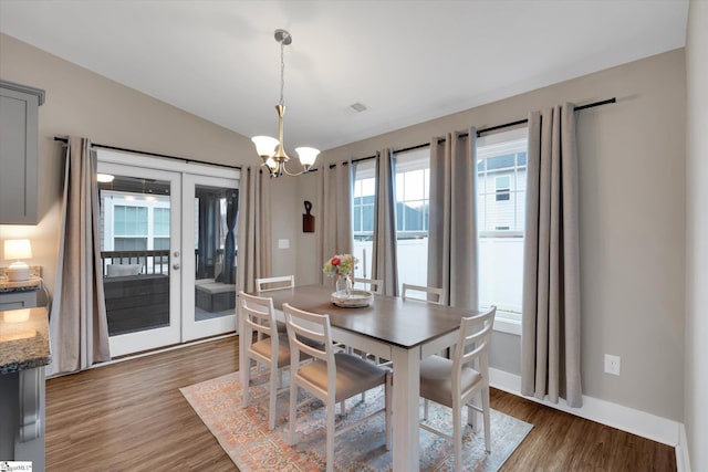 dining space with dark hardwood / wood-style flooring, vaulted ceiling, and a notable chandelier