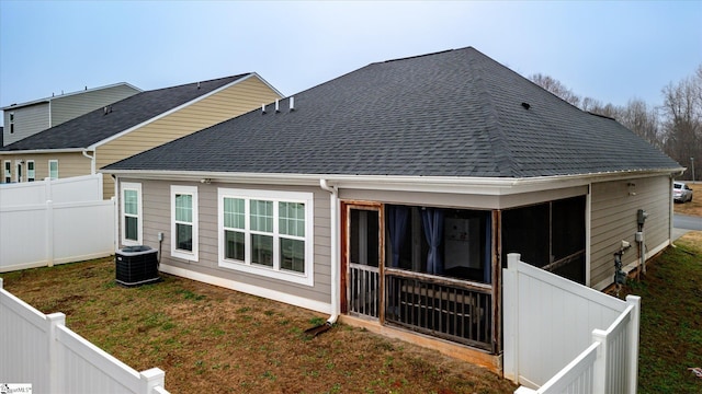 rear view of property with a sunroom, central air condition unit, and a lawn