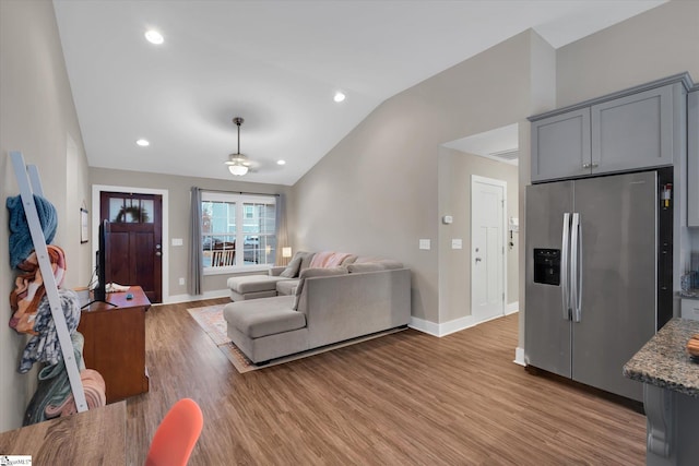 living room featuring ceiling fan, light wood-type flooring, and lofted ceiling