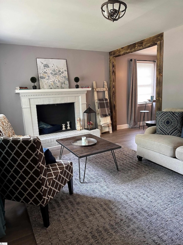 living room with a brick fireplace and hardwood / wood-style floors