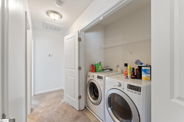 clothes washing area with washing machine and clothes dryer and light carpet