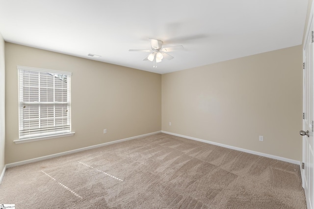 empty room with a wealth of natural light, light carpet, and ceiling fan