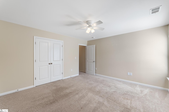 unfurnished bedroom with ceiling fan, a closet, and light carpet