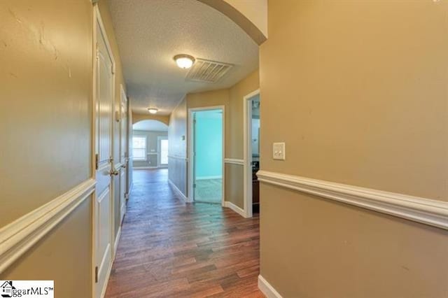 corridor with dark hardwood / wood-style flooring and a textured ceiling