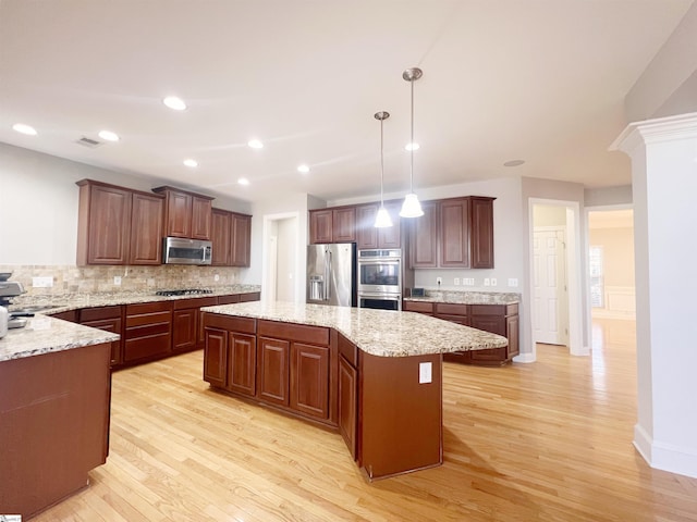 kitchen featuring hanging light fixtures, light hardwood / wood-style flooring, tasteful backsplash, a kitchen island, and stainless steel appliances