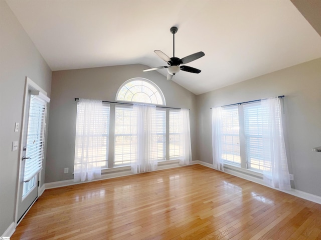 empty room featuring vaulted ceiling, light hardwood / wood-style flooring, ceiling fan, and a healthy amount of sunlight