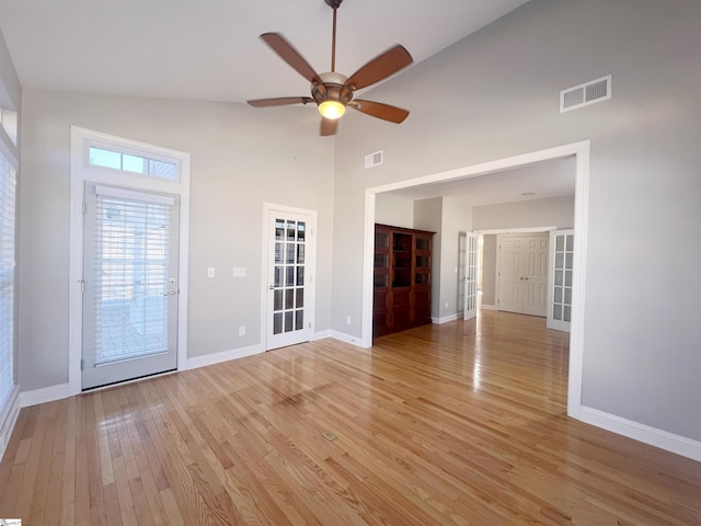 unfurnished room featuring french doors, light wood-type flooring, high vaulted ceiling, and ceiling fan