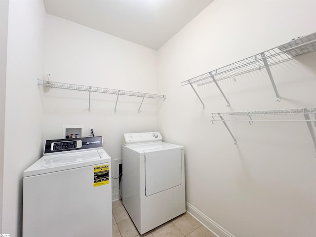 laundry area with light tile patterned floors and washing machine and clothes dryer