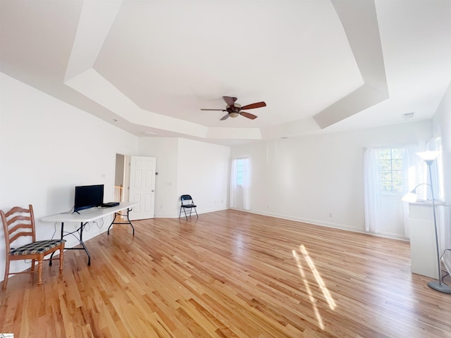 interior space with a tray ceiling, ceiling fan, and light hardwood / wood-style floors