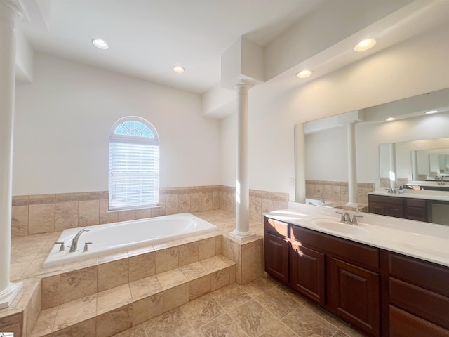 bathroom with vanity, ornate columns, and tiled tub